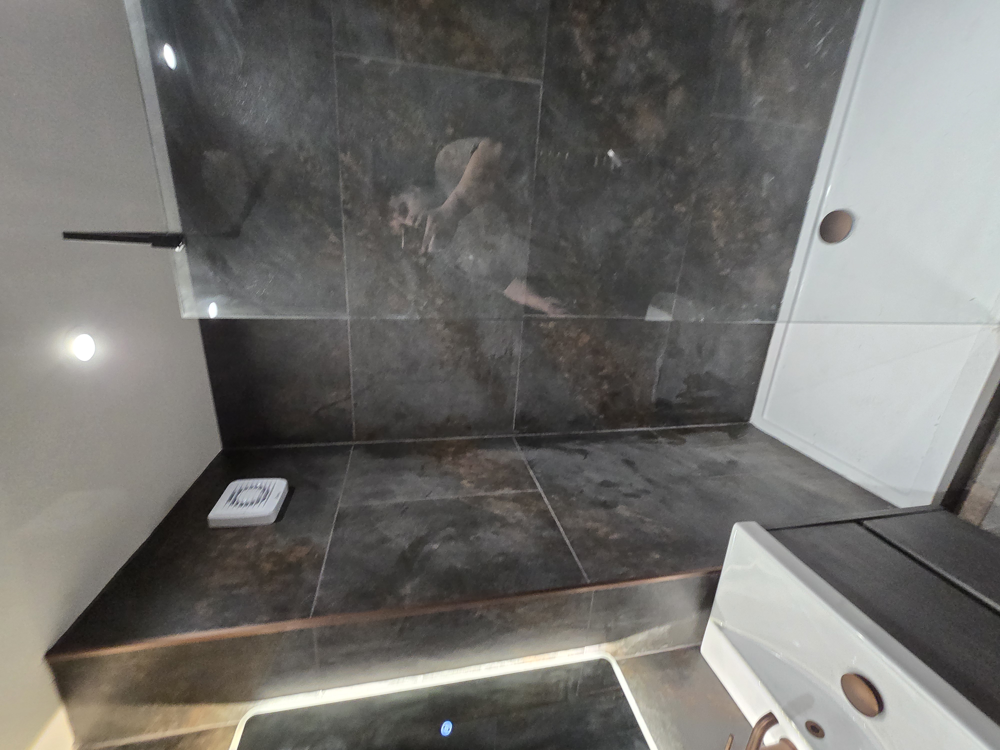 Modern bathroom shower enclosure with dark stone tiles
