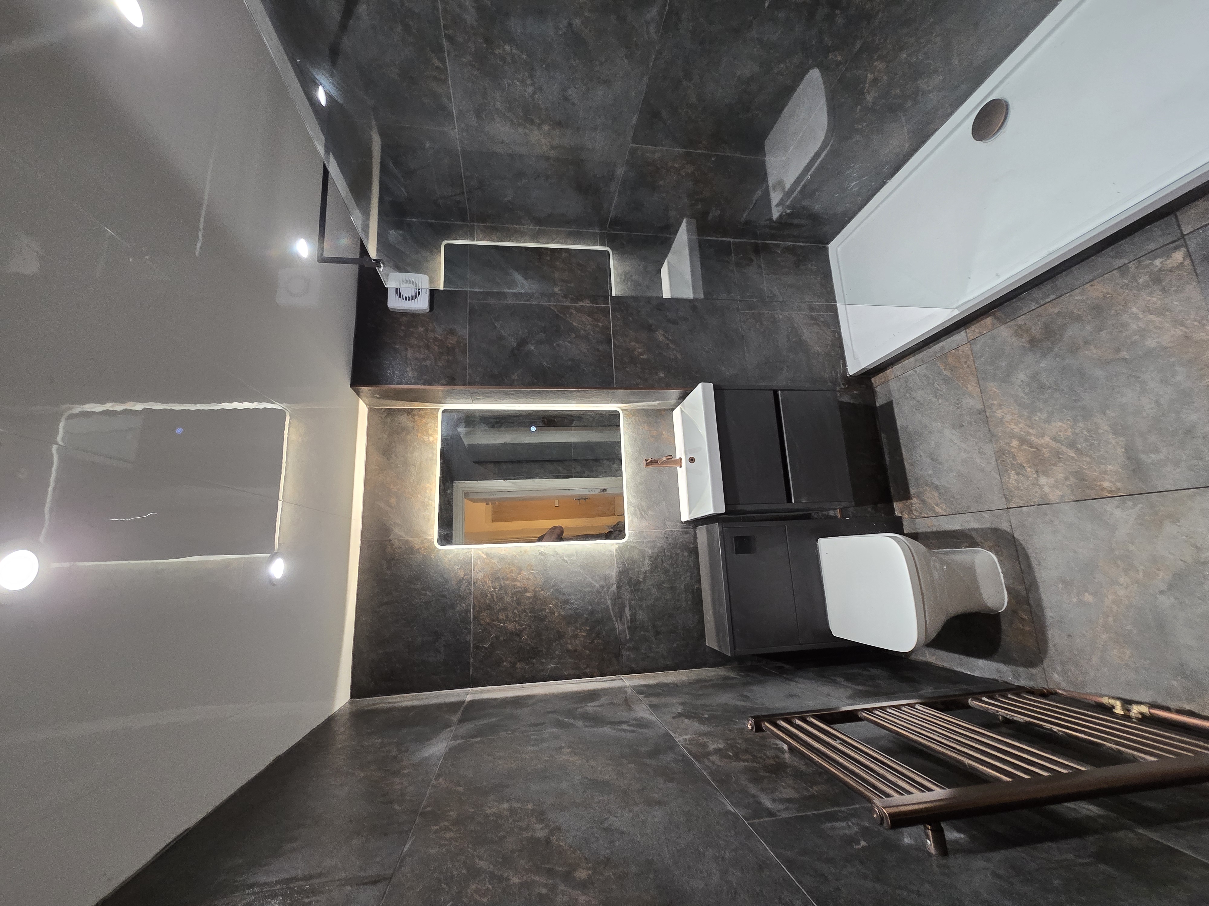 Slate tiled bathroom with backlit mirror and vanity unit