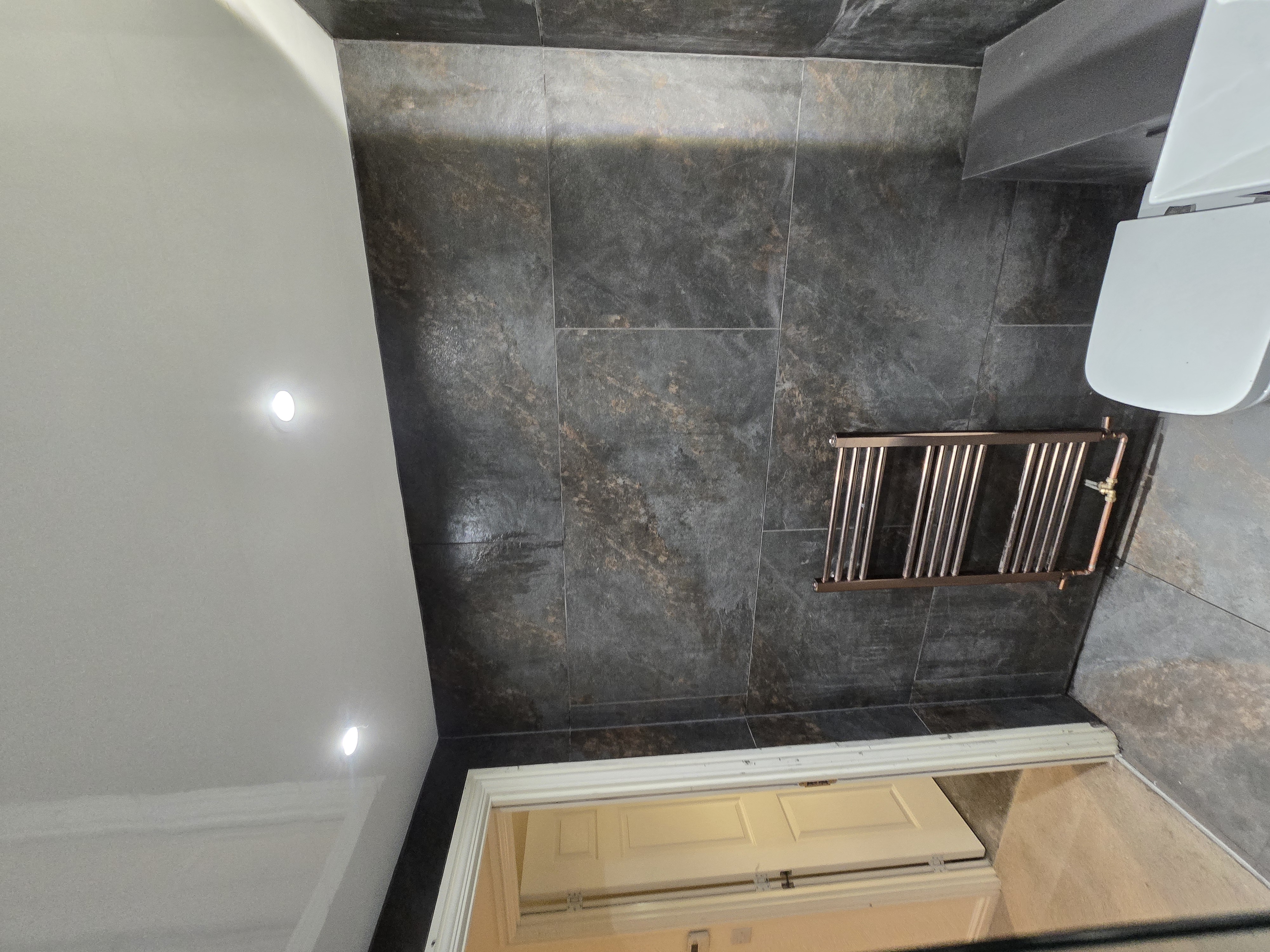 Bathroom radiator installation with dark stone wall tiles