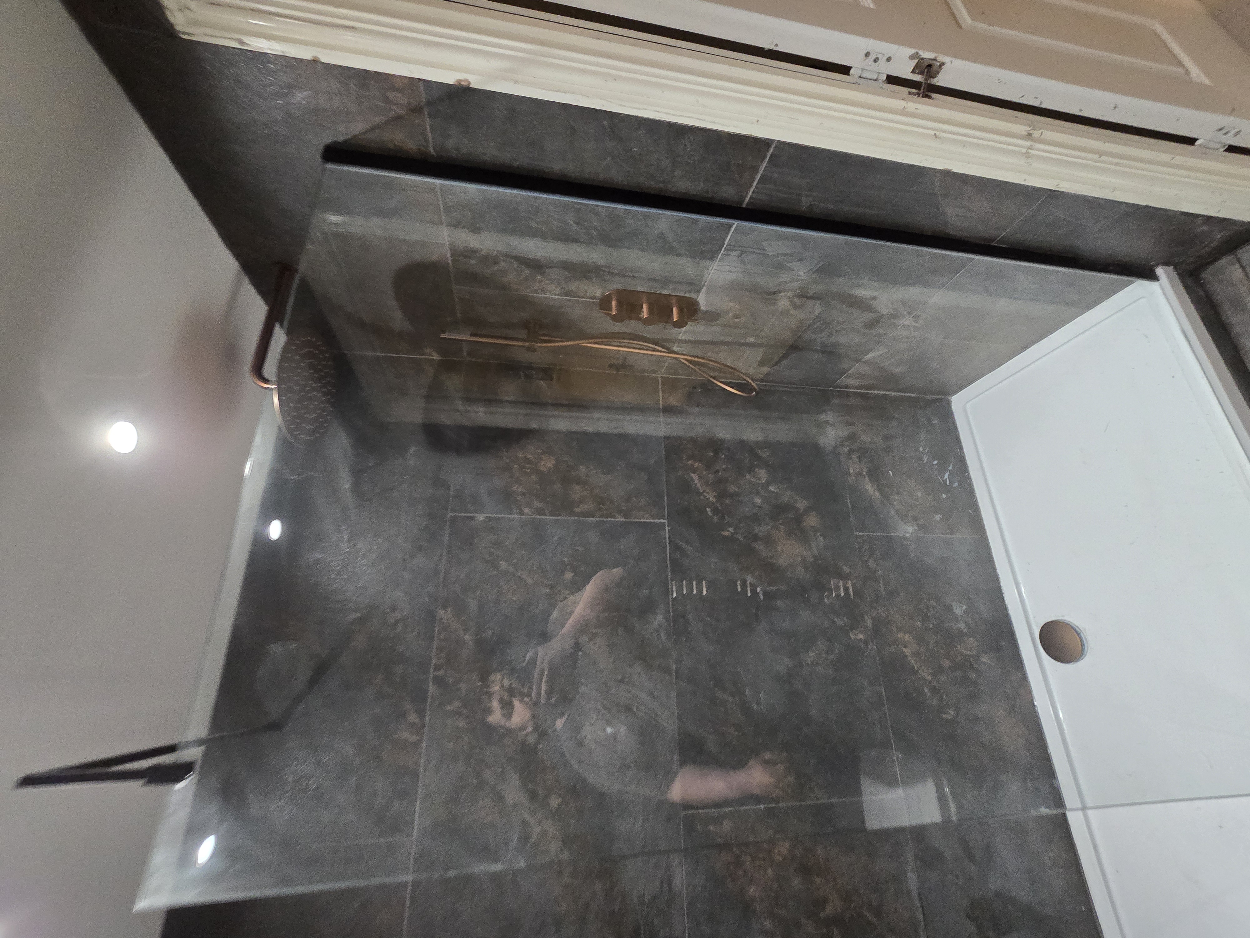 Walk-in shower with copper fixtures and glass screen