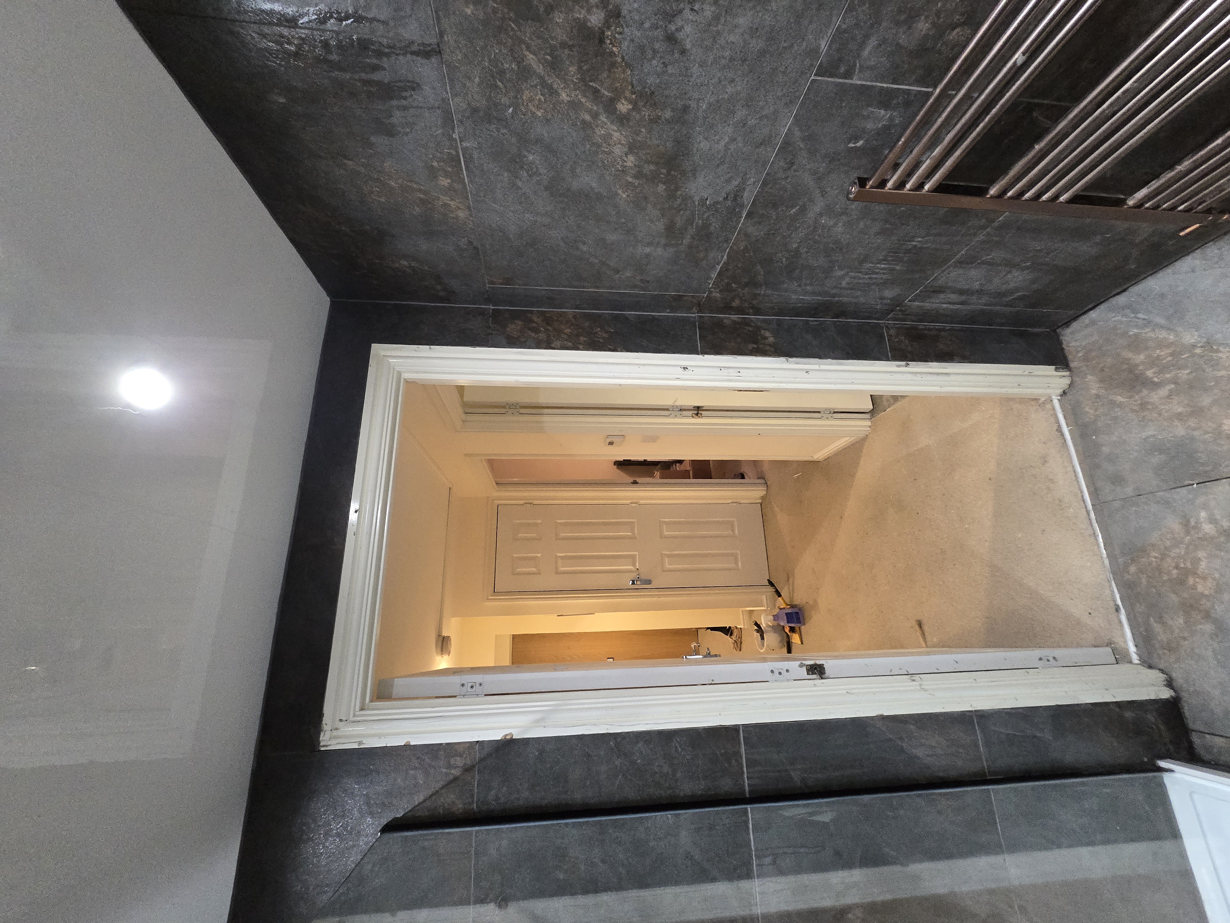 Bathroom doorway and tiling with copper towel rail