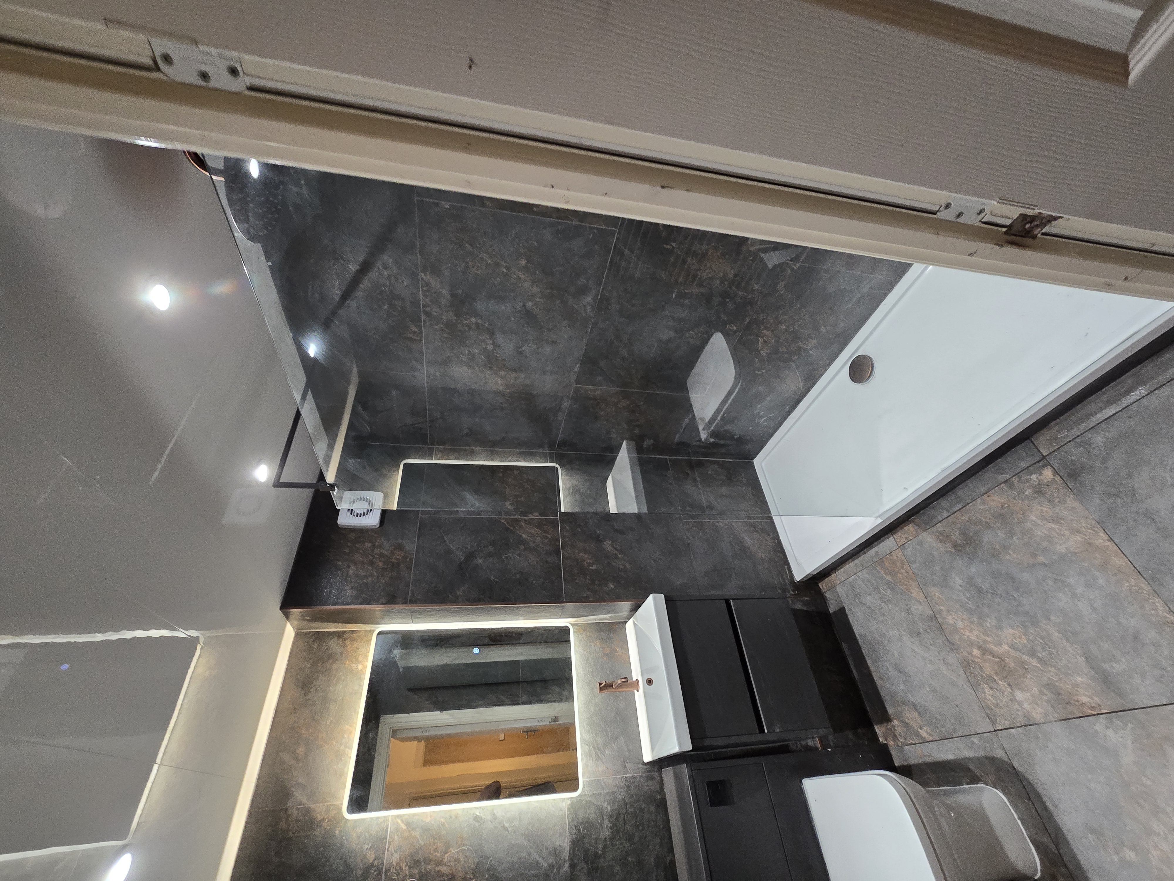 Full bathroom renovation with dark tiles and modern fixtures